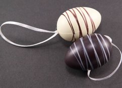 Eggs decorated with white and milk chocolate on a bow - dark brown, white