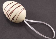 Eggs decorated with white and milk chocolate on a bow - dark brown, white